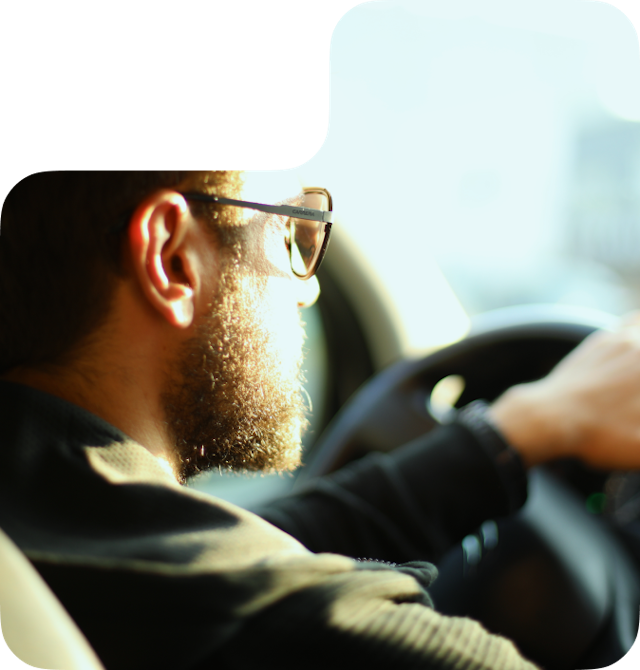 A bearded man driving a car