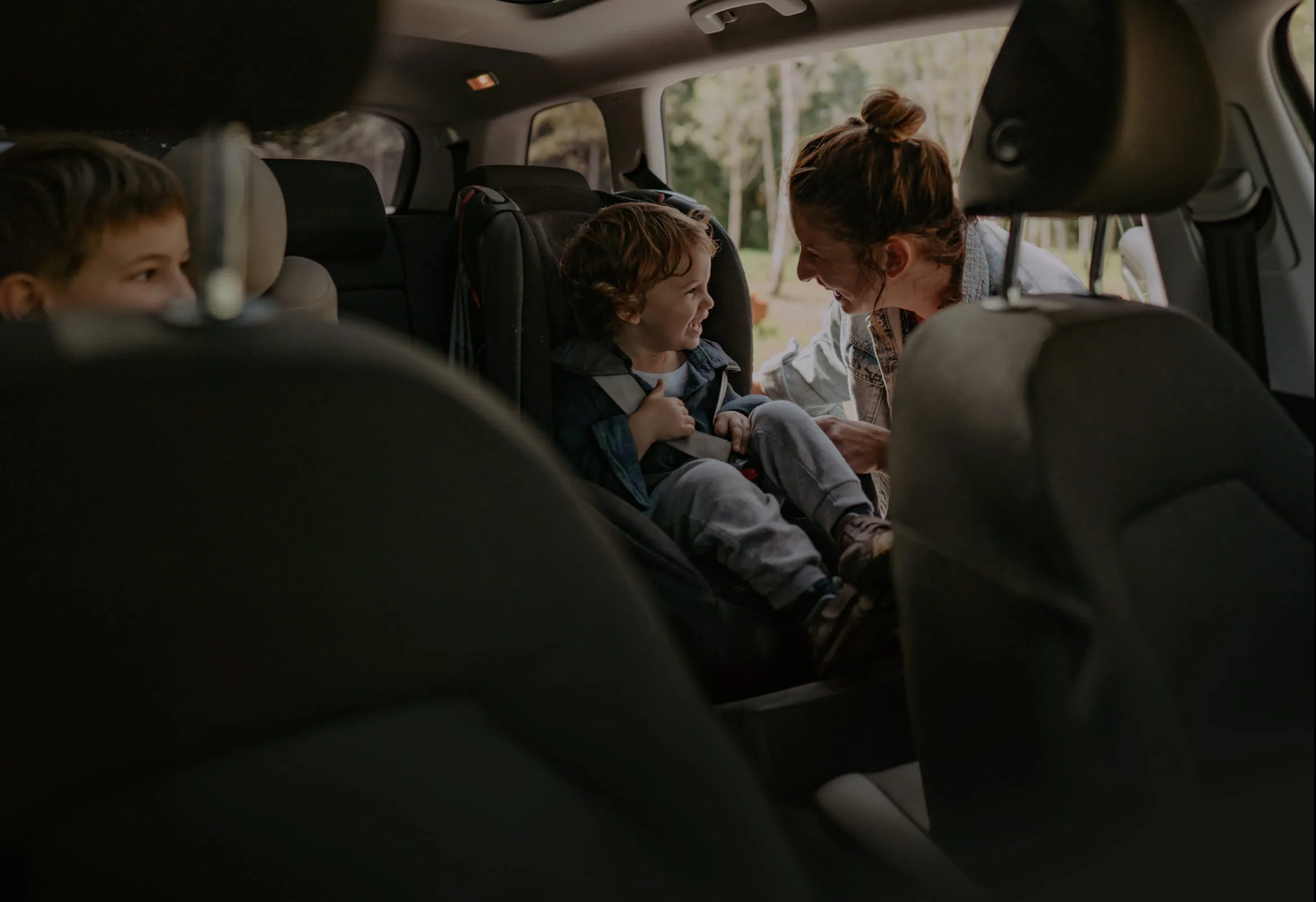 A mom strapping in a child into the backseat